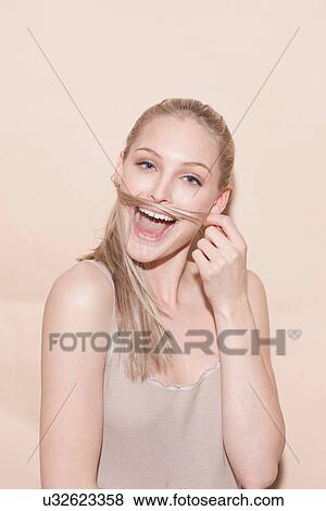 Stock Photo - Portrait of young blonde woman playing with hair. Fotosearch