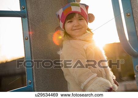 Stock Photo - Portrait of young girl in sheepskin coat in playground. Fotosearch