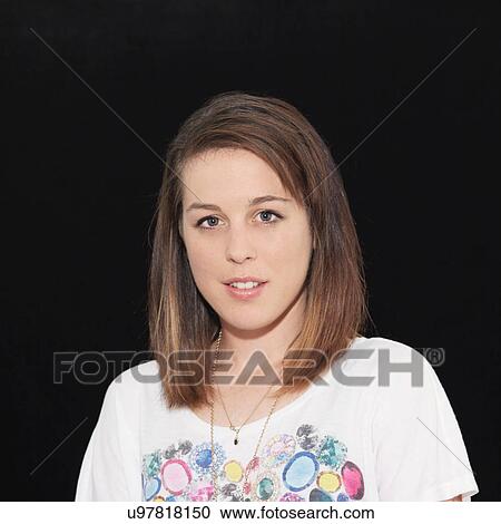 Stock Image - Portrait of young woman against black background. Fotosearch