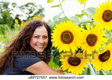 Stock Photo - Portrait of young woman and sunflowers in allotment. Fotosearch