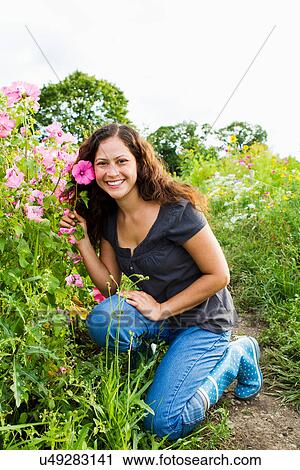 Portrait of young woman holding pink flower in allotment View Large Photo Image Stock Image - Portrait of young woman holding pink flower in allotment. Fotosearch