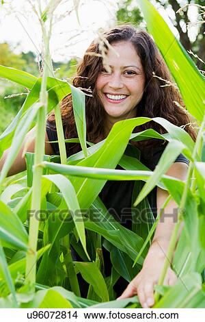 Portrait of young woman looking through green leaves in allotment View Large Photo Image Picture - Portrait of young woman looking through green leaves in allotment. Fotosearch