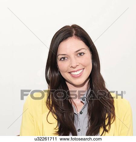 Stock Image - Portrait of young woman smiling against white background. Fotosearch