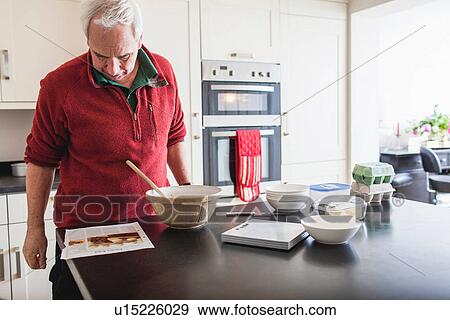 Senior male studying recipe on kitchen counter View Large Photo Image Stock Photo - Senior male studying recipe on kitchen counter. Fotosearch