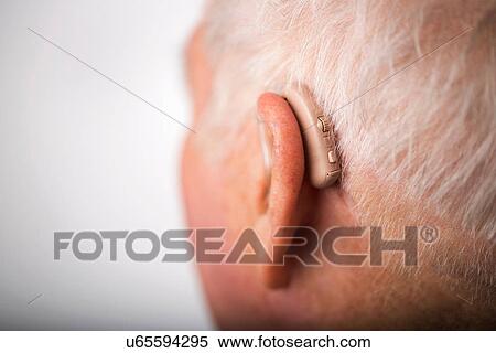 Stock Photography - Senior man wearing hearing aid, close up. Fotosearch