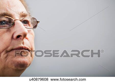 Senior woman wearing glasses and looking away against grey background View Large Photo Image Stock Photo - Senior woman wearing glasses and looking away against grey background. Fotosearch