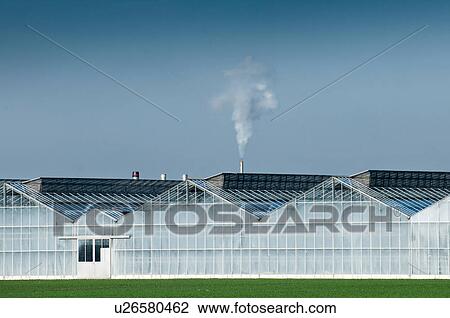 Stock Image - Smoke from large industrial greenhouse. Fotosearch