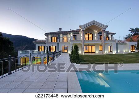 Stock Photograph - Swimming pool of luxury villa at dusk. Fotosearch