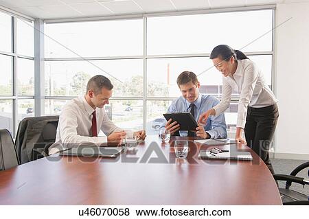 Three business colleagues in office meeting using digital tablet View Large Photo Image Stock Photo - Three business colleagues in office meeting using digital tablet. Fotosearch