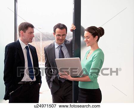 Three colleagues talking, woman holding laptop View Large Photo Image Stock Photo - Three colleagues talking, woman holding laptop. Fotosearch