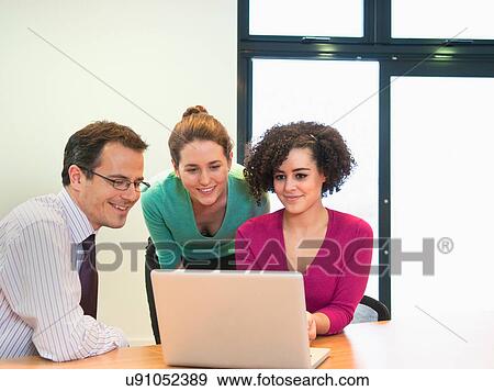 Three colleagues working on laptop in office View Large Photo Image Stock Photo - Three colleagues working on laptop in office. Fotosearch
