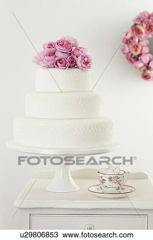 Three tiered wedding cake with pink floral arrangement and cup and saucer View Large Photo Image Stock Image - Three tiered wedding cake with pink floral arrangement and cup and saucer. Fotosearch