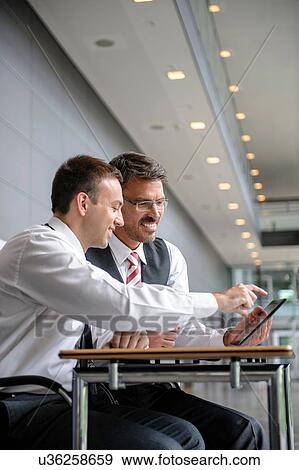 Two businessmen looking and pointing at digital tablet View Large Photo Image Stock Photo - Two businessmen looking and pointing at digital tablet. Fotosearch