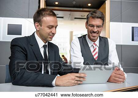 Two businessmen looking at digital tablet View Large Photo Image Stock Image - Two businessmen looking at digital tablet. Fotosearch