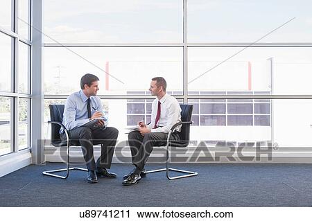 Two male business colleagues sitting on chairs View Large Photo Image Stock Image - Two male business colleagues sitting on chairs. Fotosearch