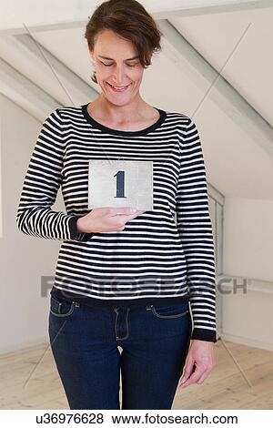 Woman holding piece of paper with number 1 View Large Photo Image Stock Photo - Woman holding piece of paper with number 1. Fotosearch