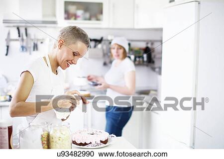 Stock Image - Woman icing cake. Fotosearch