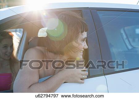 Stock Photo - Woman looking over shoulder through car window. Fotosearch