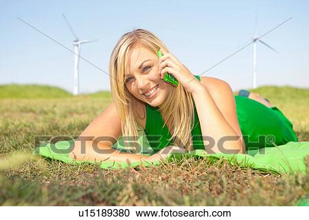Woman lying in field on green cell phone View Large Photo Image Stock Image - Woman lying in field on green cell phone. Fotosearch