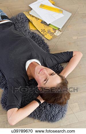 Woman lying on floor, hands behind head View Large Photo Image Stock Image - Woman lying on floor, hands behind head. Fotosearch