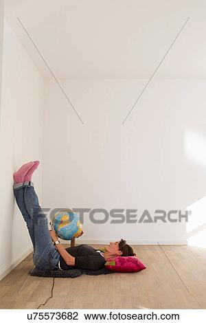 Woman lying on floor of empty room holding globe View Large Photo Image Stock Image - Woman lying on floor of empty room holding globe. Fotosearch