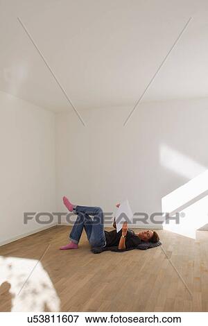 Woman lying on floor of empty room reading document View Large Photo Image Stock Photo - Woman lying on floor of empty room reading document. Fotosearch