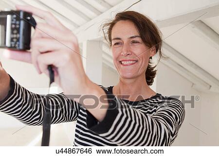 Woman photographing self with digital camera View Large Photo Image Stock Photograph - Woman photographing self with digital camera. Fotosearch