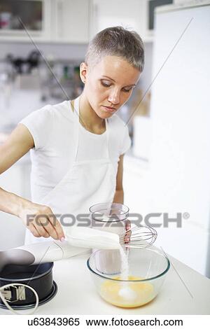 Stock Photography - Woman pouring sugar into mixing bowl. Fotosearch