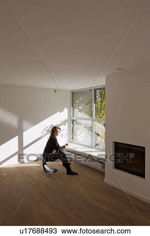 Woman sitting on chair in empty room View Large Photo Image Stock Image - Woman sitting on chair in empty room. Fotosearch