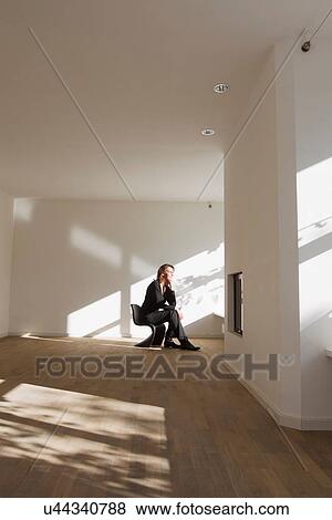 Woman sitting on chair in empty room View Large Photo Image Stock Photo - Woman sitting on chair in empty room. Fotosearch