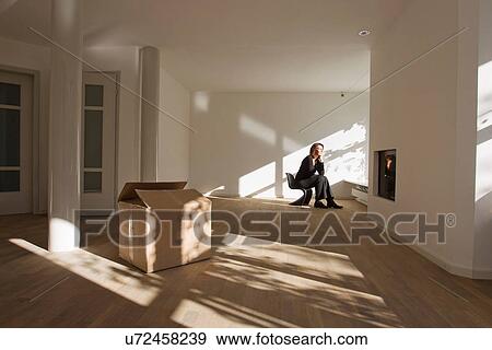 Woman sitting on chair in empty room View Large Photo Image Stock Photo - Woman sitting on chair in empty room. Fotosearch