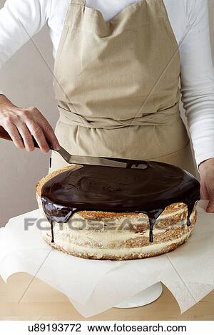 Stock Image - Woman spreading melted chocolate on cake. Fotosearch