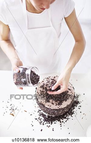 Stock Photo - Woman sprinkling chocolate chips on cake. Fotosearch