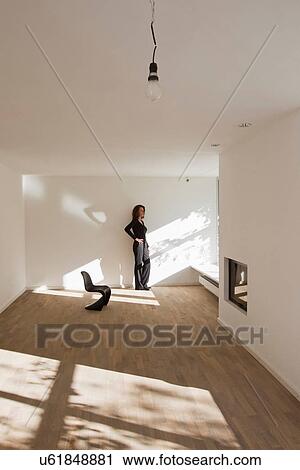 Woman standing by wall in empty room View Large Photo Image Stock Image - Woman standing by wall in empty room. Fotosearch