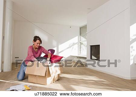 Woman unpacking cardboard box in empty room View Large Photo Image Stock Image - Woman unpacking cardboard box in empty room. Fotosearch
