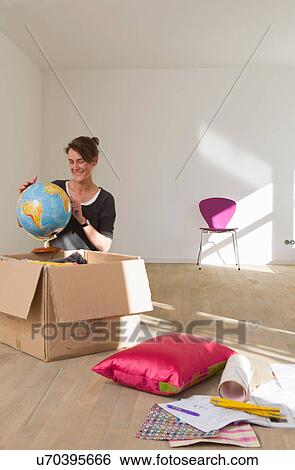 Stock Photograph - Woman unpacking globe from cardboard box. Fotosearch