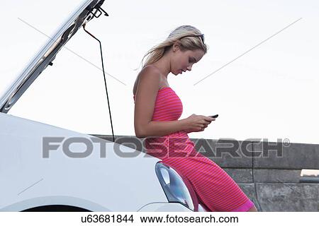 Woman using cell phone with broken down car View Large Photo Image Picture - Woman using cell phone with broken down car. Fotosearch