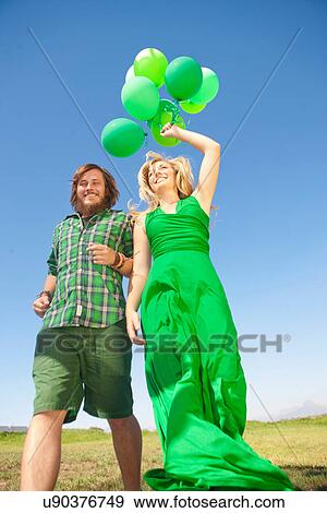 Young couple in field, woman holding green balloons View Large Photo Image Stock Photo - Young couple in field, woman holding green balloons. Fotosearch