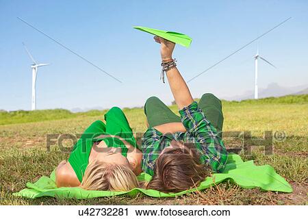 Young couple lying in field, man holding paper aeroplane View Large Photo Image Stock Image - Young couple lying in field, man holding paper aeroplane. Fotosearch