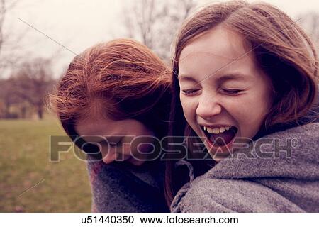 Young friends wrapped in a blanket and laughing outdoors View Large Photo Image Stock Image - Young friends wrapped in a blanket and laughing outdoors. Fotosearch