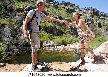 Young hiker assisting woman over rocks View Large Photo Image Stock Image - Young hiker assisting woman over rocks. Fotosearch