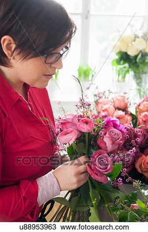 Stock Image - Young woman arranging fresh flowers into bouquet. Fotosearch