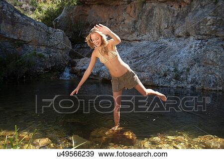 Stock Photo - Young woman balancing on rock in stream. Fotosearch