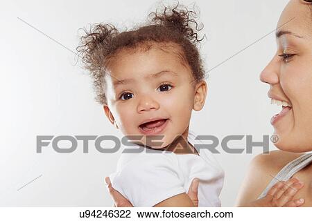 Young woman holding baby daughter in studio View Large Photo Image Stock Image - Young woman holding baby daughter in studio. Fotosearch