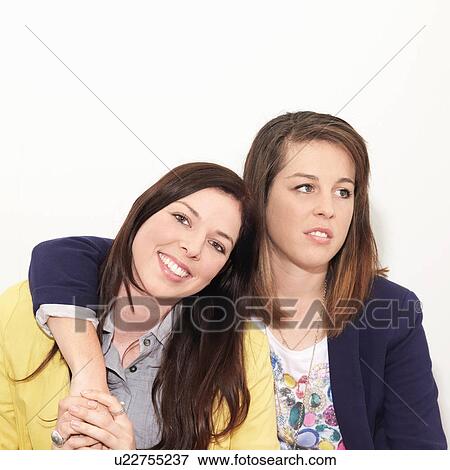 Young woman looking unimpressed next to friend against white background View Large Photo Image Stock Photo - Young woman looking unimpressed next to friend against white background. Fotosearch