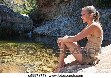 Young woman sitting on rock in stream View Large Photo Image Stock Photo - Young woman sitting on rock in stream. Fotosearch