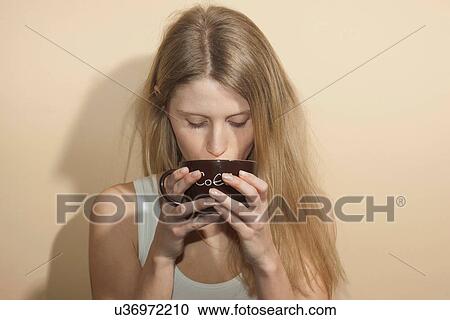 Young woman with long blonde hair drinking from coffee cup View Large Photo Image Stock Image - Young woman with long blonde hair drinking from coffee cup. Fotosearch
