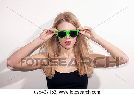 Stock Image - Young woman with long blonde hair wearing sunglasses. Fotosearch