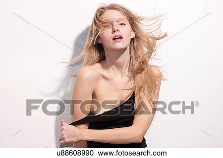 Stock Image - Young woman with long blonde hair undressing. Fotosearch