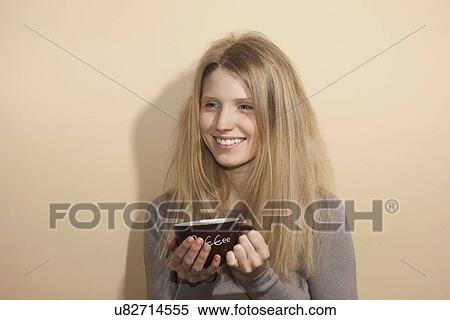 Stock Photography - Young woman with long blonde hair holding coffee cup, smiling. Fotosearch